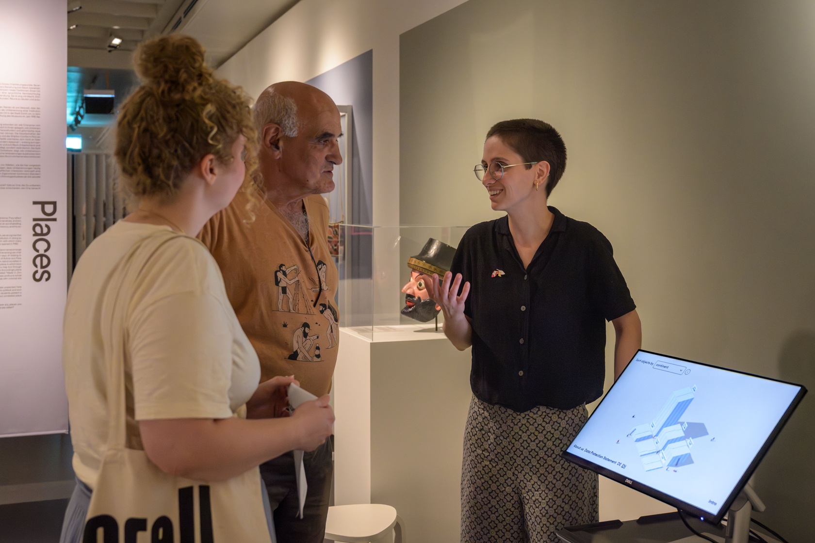A person explains the visualisation to two other people, showing it on a screen.